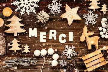 Letters Building The Word Merci Means Thank You. Wooden Christmas Decoration Like Tree, Sled And Star. Brown Wooden Background With Snowflakes