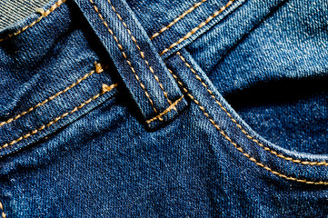 Close-up texture of blue denim stitched with orange thread