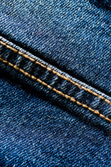 Close-up texture of blue denim stitched with orange thread