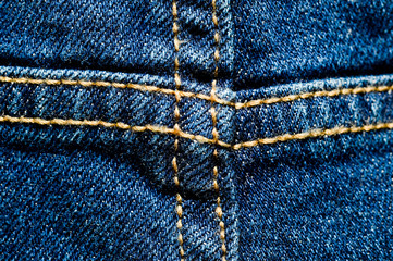 Close-up texture of blue denim stitched with orange thread