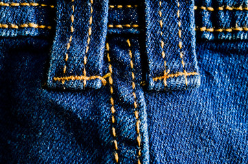 Close-up texture of blue denim stitched with orange thread
