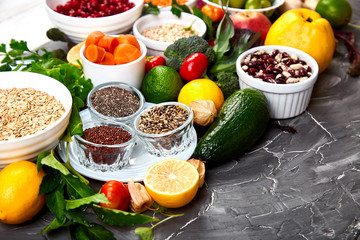 Healthy vegan food. Assortment of organic vegetables and fruits with legumes, nuts on grey background. Top view, flat lay, copy space.