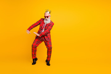 Fototapeta na wymiar Full body photo of funny grandpa white beard dancing strange youngster moves little drunk wear crown sun specs gingham red costume isolated yellow color background