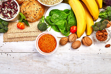 Set of high dietary fibre health food product concept with fruit, vegetables, whole wheat bread, legumes, cereals, nuts and seedson white wooden background . Top view, flat lay, copy space..