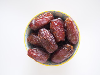 Top view of bowl with dried dates fruit or date palm isolated on white background