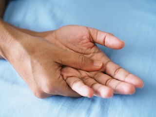 Thai person on blue bed and palm massage to relieve acute hand pain, Medical health concept.