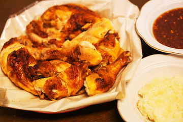 Grilled chicken and sticky rice and sauce on a plate.