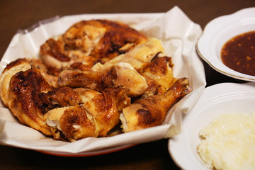 Grilled chicken and sticky rice and sauce on a plate.