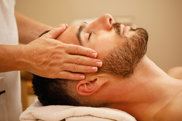 Close-up of relaxed man during head massage at spa center.