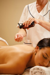 Unrecognizable massage therapist pouring oil before a treatment at the spa.