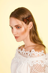Medium close-up shot of a young stylish European girl with a cambered hair clip in her long straight hair. The hairpin is made of burgundy glazy material in the form of a bow-knot with a black stripe. © RedUmbrella&Donkey