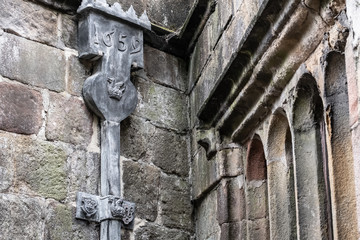 Detailed view of medieval leaded guttering seen on the outside of a medieval building. The date made can be seen on the gutter and royal crests further down.