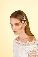 Medium close-up shot of a young stylish European girl with a cambered hair clip in her long straight hair. The hairpin is made of beige glazy material in the form of a bow-knot with a black stripe.  © RedUmbrella&Donkey