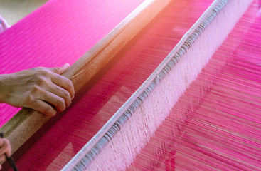 Woman working on weaving machine for weave handmade fabric. Textile weaving. Weaving using...