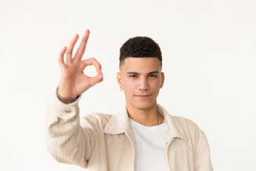 Fototapeta premium Confident man showing ok sign. Portrait of handsome serious young man showing ok symbol with hand and looking at camera. Gesture concept