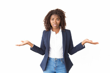 Worried confused female manager making do not know gesture. Young black business woman standing...