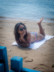 Asian Female with Dark Glasses and Bikini Lies on White Towel on Tropical Beach (Vertical)