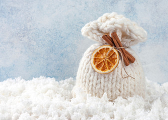 Christmas composition. Festive bag decorated with dried orange and cinnamon sticks on blue background. Copy space