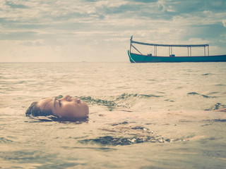 Face of an Asian Woman Floating in the Sea with Fishing Boat Nearby