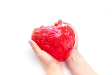 Modern toy called slime. Heart made of transparent red slime. Hands holding a mucus isolated on a white background.	