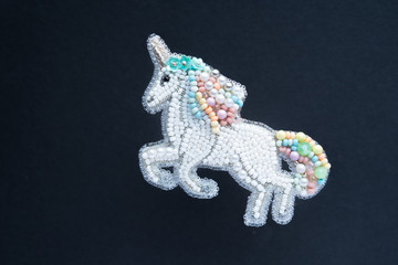 Capricorn, brooch embroidered with beads on dark background.