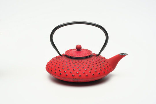 Red cast iron teapot on a white background.