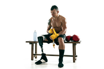 Full length portrait of muscular sportsman with prosthetic leg, copy space. Male boxer in gloves preparing for practicing. Isolated on white studio background. Concept of sport, healthy lifestyle.