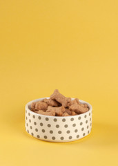 Dog food in a white bowl on a yellow background
