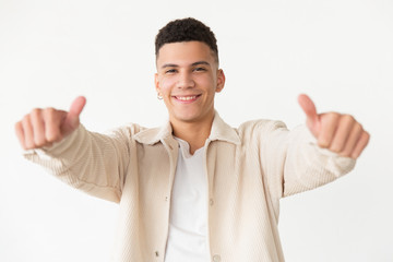 Cheerful young man showing thumbs up. Portrait of handsome happy young man showing thumbs up and smiling at camera on grey background. Gesture concept