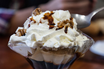 Copa de helado con nata y nueces y gotas de caramelo