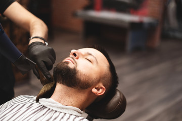 Shaving a beard in a barbershop with a dangerous razor. Barber Shop Beard Care. Drying, cutting, cutting a beard. Selective focus.