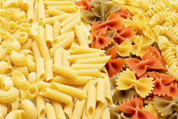 Types of uncooked pasta. Pasta penne, fusilli, color farfalle and chifferi dry. Flat lay, top view, filled frame