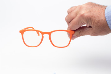 Gafas y lentes de colores y montura de plástico, de diseño, sobre fondo blanco y en la mano de...