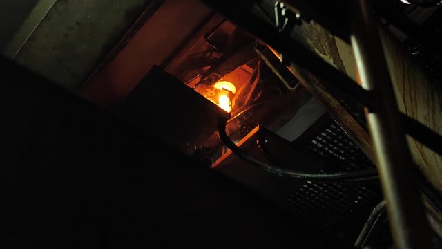 Burning blanks of glass bottles in an industrial stove in slowmotion glassworks