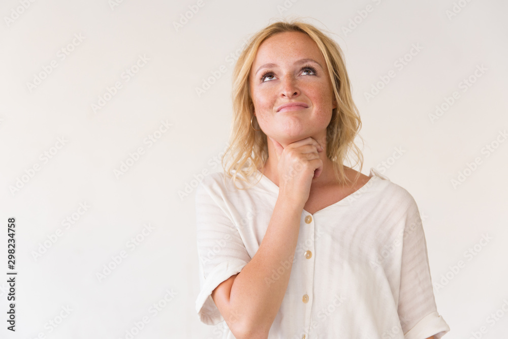 Wall mural happy cheerful young woman looking up at copy space. beautiful woman in casual posing isolated over 