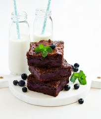 Chocolate brownies with blueberries and cream filling. Dark background.