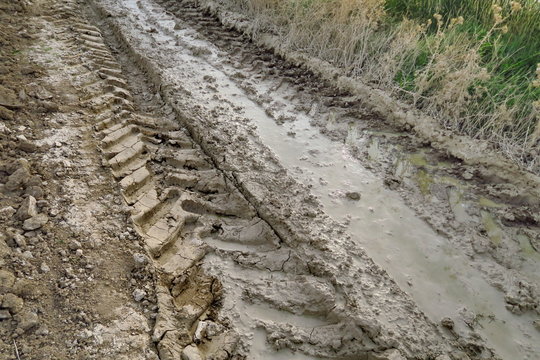 Traces de pneus dans la boue d'un chemin de terre.