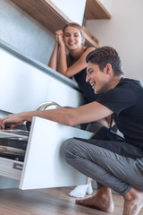 happy husband gets the dishes out of the dishwasher