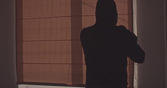 A man in black gloves opens a window. CSI Hired assassin getting ready for a shot, killer.