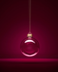 Glass christmas bauble hanging in front of luxury dark purple background.