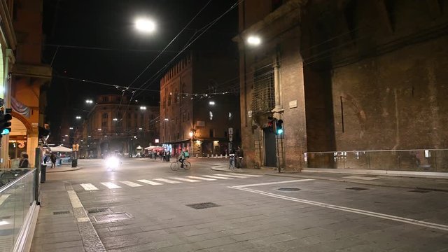 Bologna, Italy - October 2019 - Unknown people walk in the evening among the buildings and monuments of the historic city center, followed by the shadows of the night