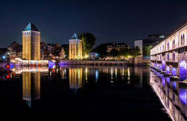 Night view of the Ponts Couverts (left) and Vauban Dam (right) illuminated in Strasbourg, France, a set of historic monuments over the river Ill at the entrance of the Petite France historic quarter.