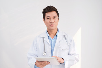 Asian smart doctor standing and holding tablet at hospital