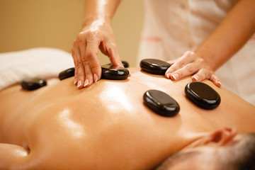 Close-up of man having hot stone therapy at the spa.