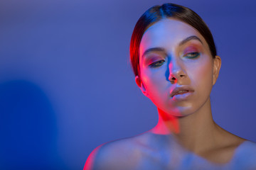 Portrait of a young woman model with natural make-up colored red blue light