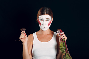 Young woman applying make-up, paints face with beet and makeup. How not to do make up concept.