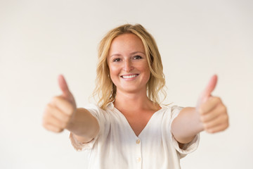 Happy woman showing thumbs up. Portrait of cheerful young blonde woman showing thumbs up and smiling at camera isolated on grey background. Gesture concept