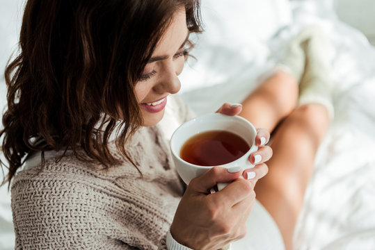 attractive woman in grey sweater holding cup of tea at morning