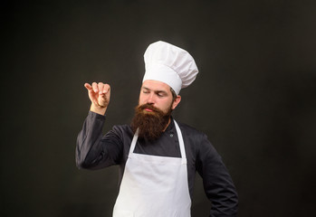 Handsome bearded chef in uniform spilling salt. Man chef in restaurant kitchen preparing food...