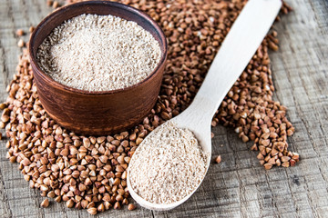 Buckwheat flour in a bowl near the buckwheat grain and a spoon with flour. A pile of buckwheat flour.